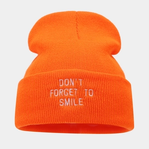 Detailed view of orange beanie featuring white embroidered Don't Forget To Smile text
