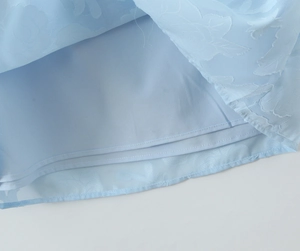 Détail de la robe en dentelle bleu clair avec texture jacquard et doublure de qualité