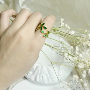 Macro shot of an adjustable gold-copper ring with green enamel leaf design on hand