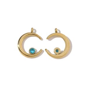Detail of two gold crescent moon pendants with blue gemstone inlays on a white background