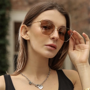 Chic model wearing golden metal cat-eye sunglasses with brown gradient lenses