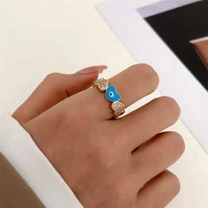 Macro shot of gold heart ring with blue evil eye enamel and shimmering cubic zirconia