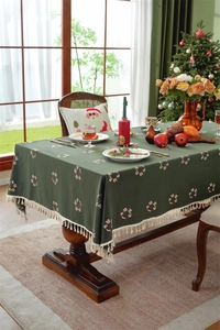 Detail of green Christmas tablecloth with wreath patterns and beige tassel fringe edges