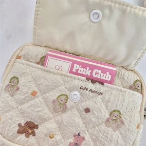 Detail of beige quilted storage bag featuring cute animal patterns and snap pocket