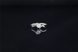 Macro shot of silver bypass moissanite ring with brilliant round cut stone on black