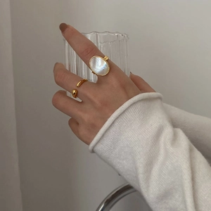 Detail of elegant gold-plated ring set featuring a large oval mother of pearl stone