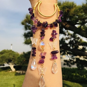 Detail of golden arm cuff with purple crystals and butterfly teardrop crystal pendants