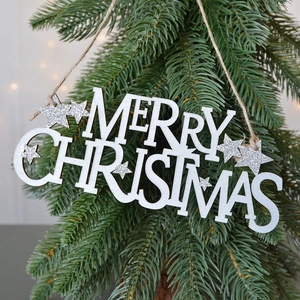 Targa natalizia in legno bianco con stelle glitterate appesa a un albero di Natale