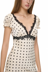 Detail of V-neck beige polka dot dress with black lace trim and puffed short sleeves