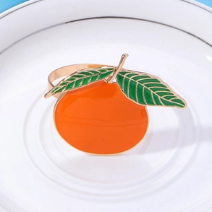 Detail of metal orange fruit napkin ring with vibrant orange enamel and gold finish