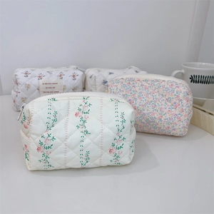 Vue détaillée de trousses de maquillage matelassées à motifs floraux avec fermetures à glissière