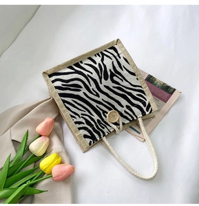 Detail of zebra print canvas tote featuring natural wood button and woven cotton rope handle