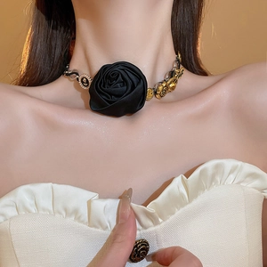 Dettaglio del choker rosa nera con maglie in metallo dorato e perle bianche