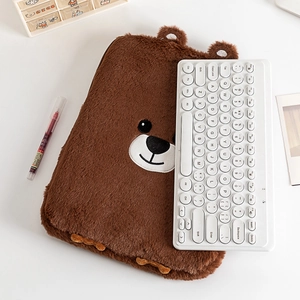 Détail de la pochette d'ordinateur ours en peluche marron avec broderie et bureau épuré
