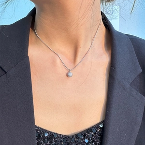 Nahaufnahme einer silbernen Schlangenkette mit Kristallkugel-Anhänger an einem Modell