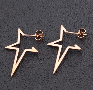 Macro shot of rose gold star stud earrings with hollow design on black background