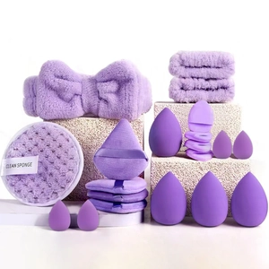 Detailed set of purple makeup sponges, puff, and plush headband on stone props
