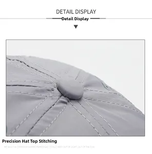 Close-up of top button and reinforced stitching on a grey quick-dry baseball cap
