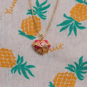 Golden geometric necklace with pink and orange enamel pendant and small gemstones