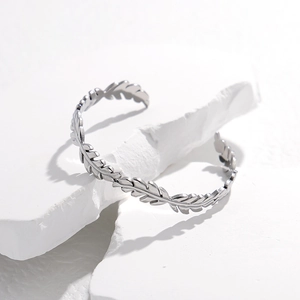 Dettaglio ravvicinato di un bracciale aperto in argento a forma di foglia su pietra bianca