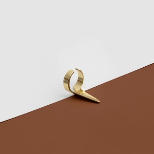 Gros plan d'une bague dorée à pointes montrant un design géométrique et un fini poli