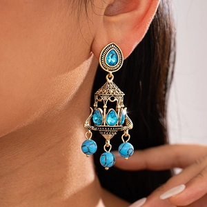 Macro shot of vintage gold chandelier earrings with blue teardrop crystals and turquoise beads
