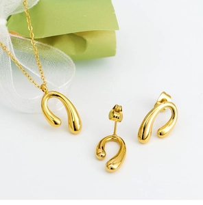 Detailed view of polished gold U-shape necklace and earring set on white background