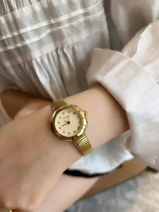 Detail of elegant gold octagon watch with rhinestone markers on a stainless elastic band