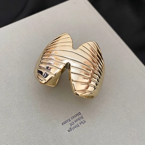 Macro shot of gold wide ring with textured ridges on a grey design book background