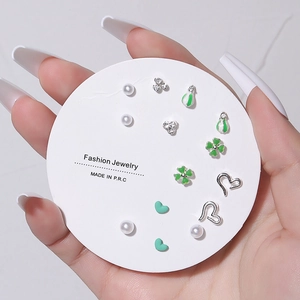 Detail of 7-pair silver earring set featuring pearls, clover, and heart designs on a card