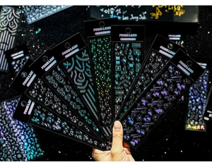 Macro view of holographic laser stickers with stars and hearts on black cardstock