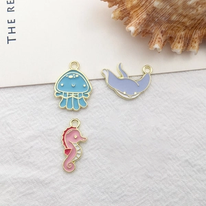 Macro detail of enamel ocean charms including blue jellyfish, purple ray and pink seahorse