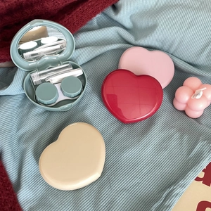 Macro shot of candy-colored heart contact lens cases with built-in mirrors and tool kits