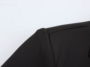 Close-up of the woven black shoulder seam and texture of the long double-breasted blazer