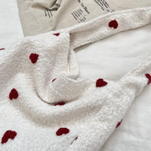 Close-up of white shearling tote bag featuring detailed red plush heart embroidery