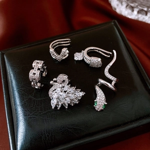 Close-up of sparkling zircon ear cuff set featuring swan, snake, and V-shaped silver designs