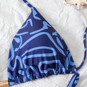 Detail of blue abstract wave print bikini top with golden cylinder metal accents