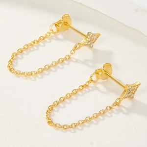 Detail view of gold star stud earrings with chain connection and small zircon stones