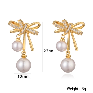 Detailed view of gold bow earrings with pearls and crystals showing 1.8x2.7cm dimensions