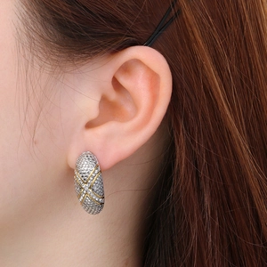 Detailed view of vintage oval stainless steel stud earrings with gold cross texture