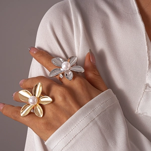 Close-up of metallic flower ring with pearl center in gold and silver finishes