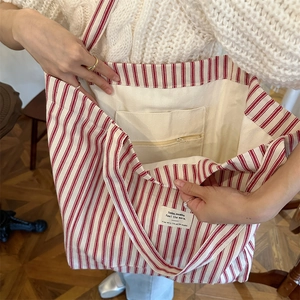 Detail view of red striped canvas tote bag showing interior zipper pocket and spacious lining