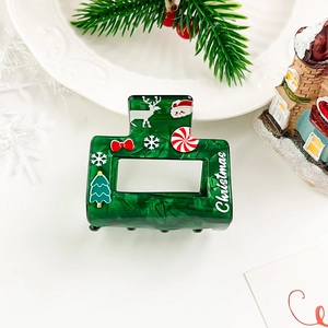 Detail of green Christmas hair claw with festive tree and reindeer patterns in holiday setting