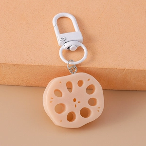 Macro detail of a realistic lotus root slice keychain with textured holes on orange background