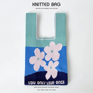 Detail of blue knitted tote bag with floral patterns and You Only Live Once text