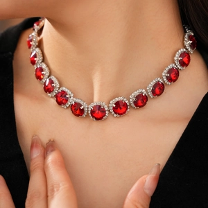 Detailaufnahme der Halskette mit facettierten roten Edelsteinen und Diamant-Heiligenschein
