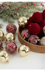 Détail de boules de Noël floquées rouges et dorées dans un panier en osier