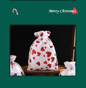 Detail of white linen Christmas gift bag with red sequin heart and drawstring closure