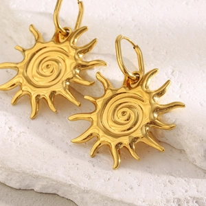 Detail of 18K gold plated stainless steel sun earrings with spiral texture on stone surface