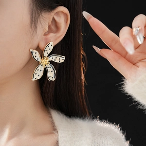 Close-up of vintage flower earrings with black polka dots and gold-toned edges